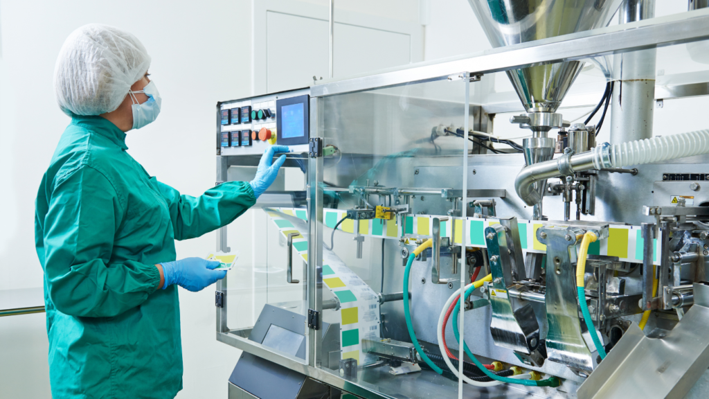 A worker in protective clothing operates machinery in a sterile manufacturing environment, demonstrating the skills required for hard-to-fill roles and overcoming position-specific barriers.